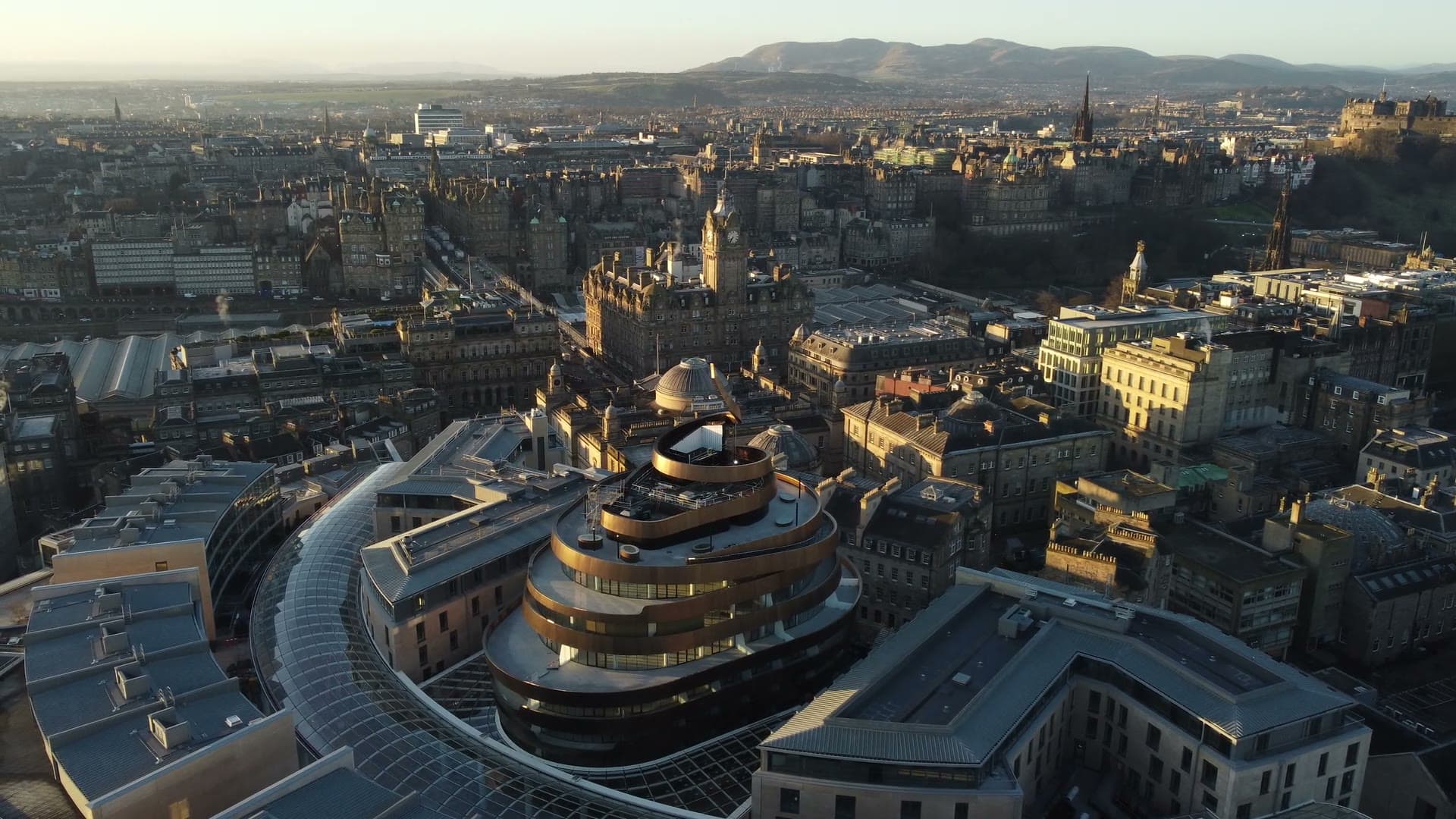 Aerial view of Edinburgh's Old Town at golden hour, looking over the rooftops toward the Balmoral clock tower and the Castle